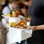 Waitress carrying two plates with meat dish