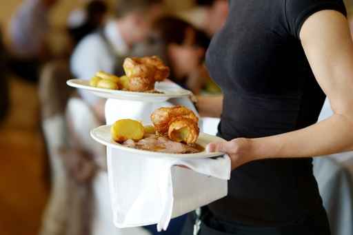 Waitress carrying two plates with meat dish